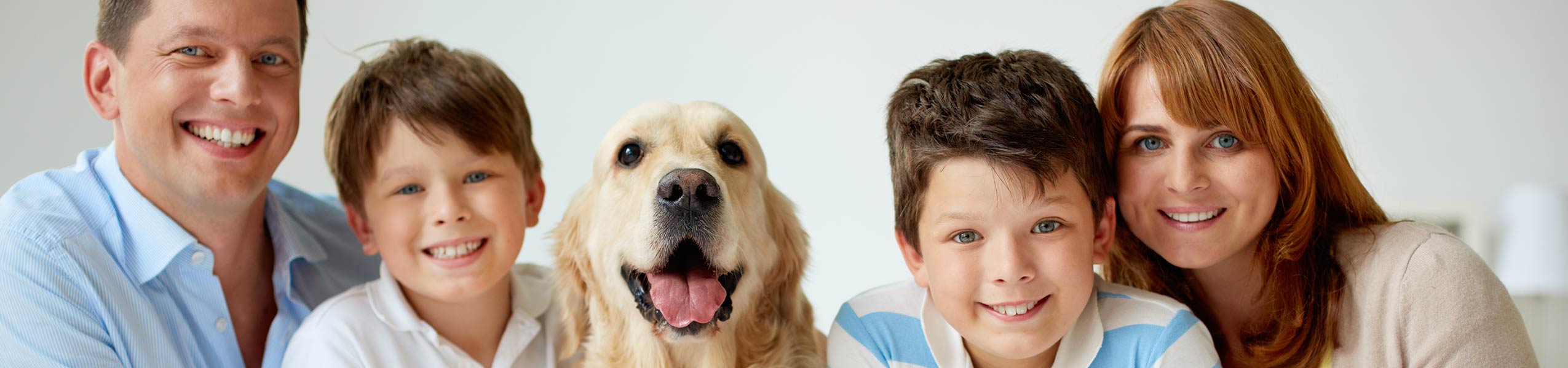 Family of four with a Golden Retriever all smiling together.